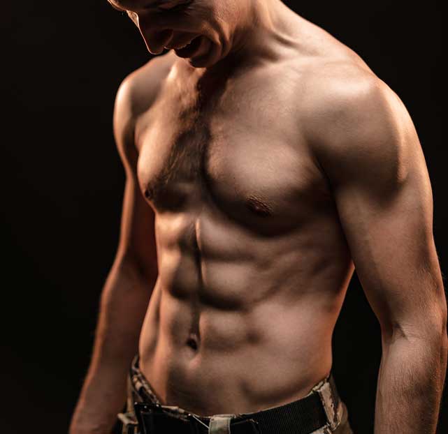 Muscular shirtless man looking down, highlighting defined abs and arm muscles against a dark background.